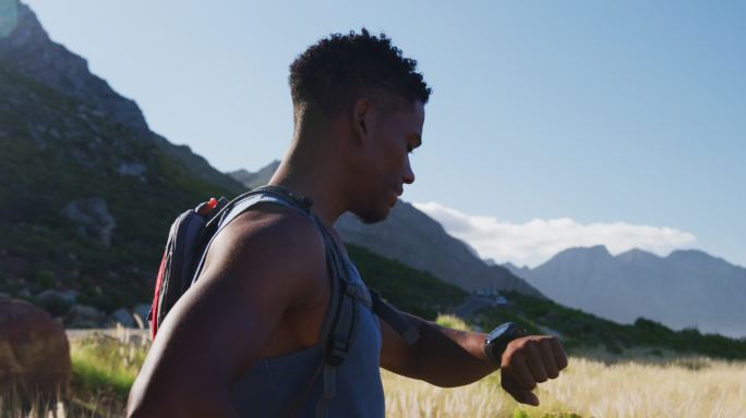 男人使用智能手表在山区乡村越野跑步。