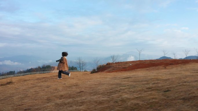 高山上奔跑的女摄影师