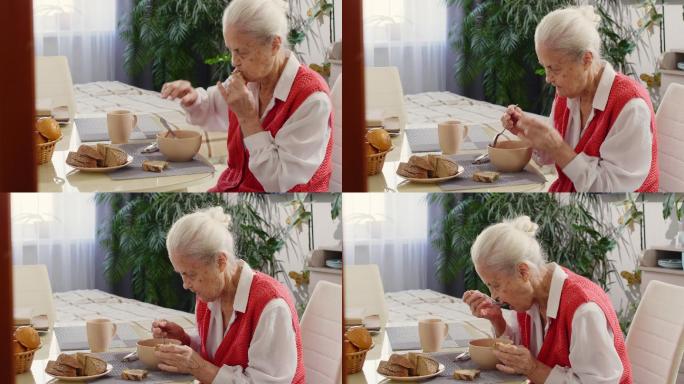 老妇人在家里喝汤吃面包