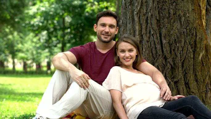 丈夫陪着怀孕的妻子坐在公园里