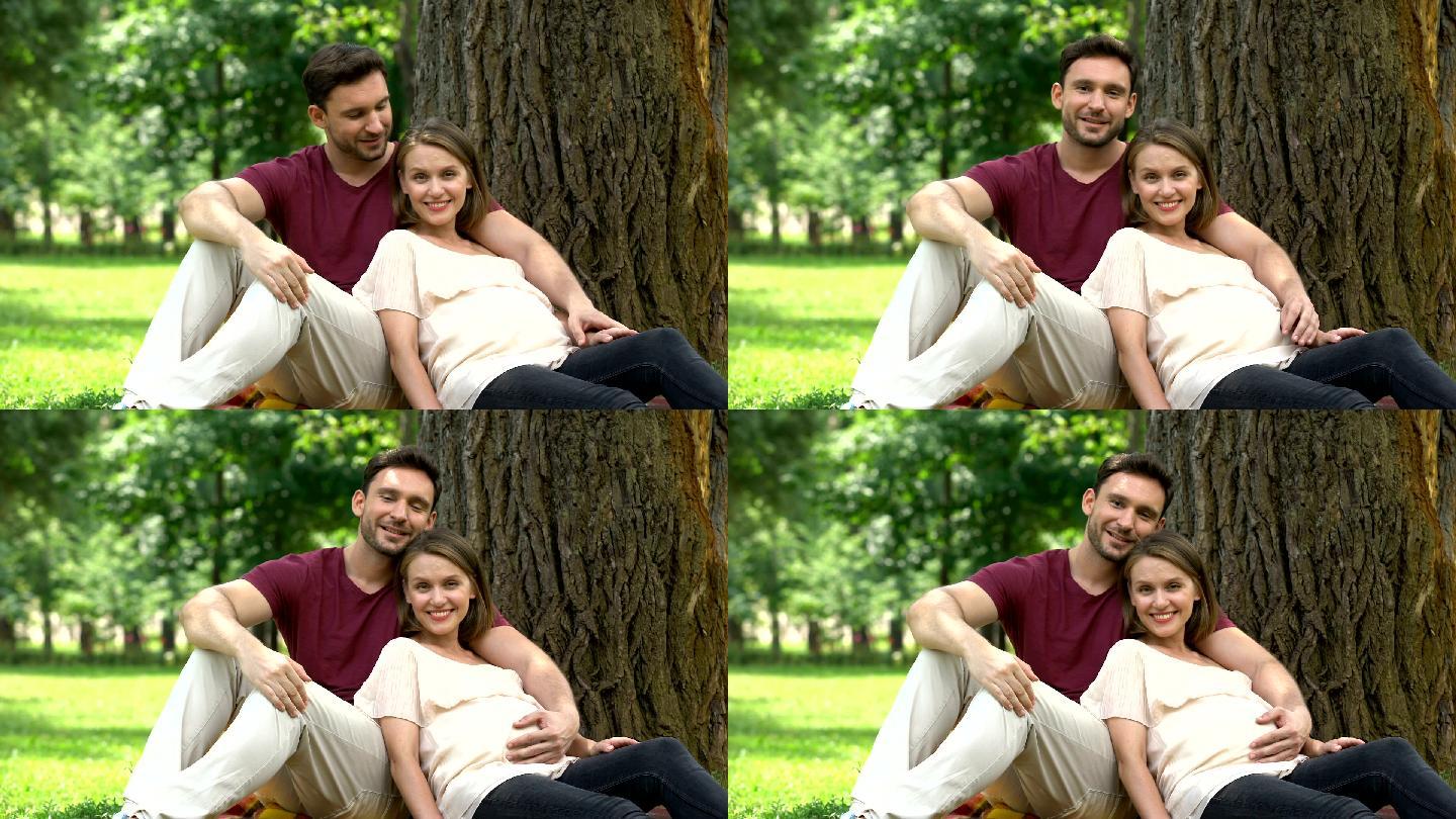 丈夫陪着怀孕的妻子坐在公园里