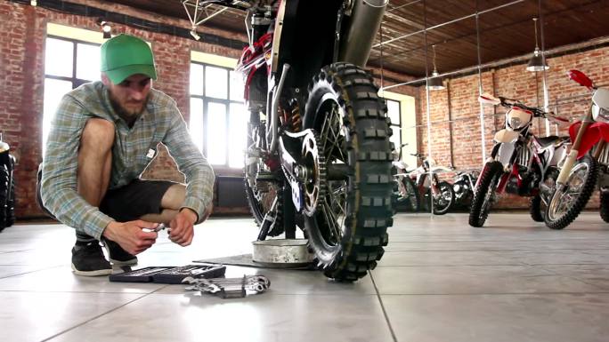 男运动员正在修理他的摩托车