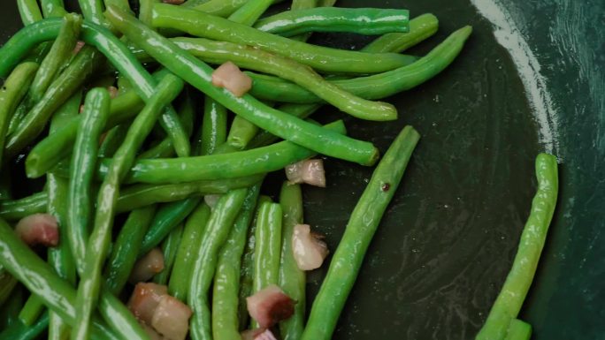 煎锅里的青豆和培根特写。