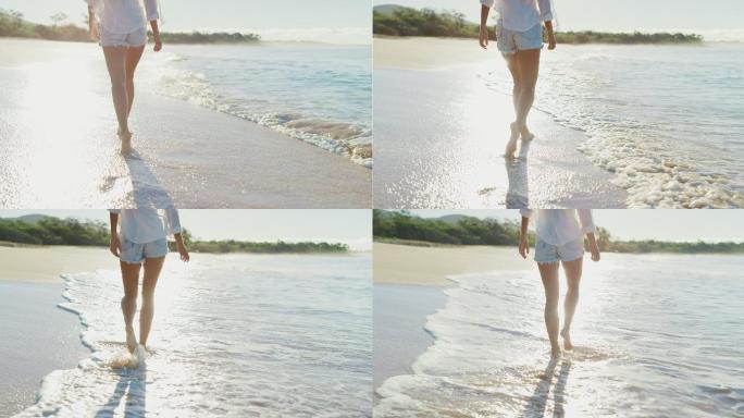 日出时年轻的女性沿着海滩漫步