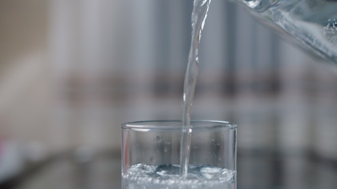 把干净的饮用水从瓶子倒进玻璃杯里