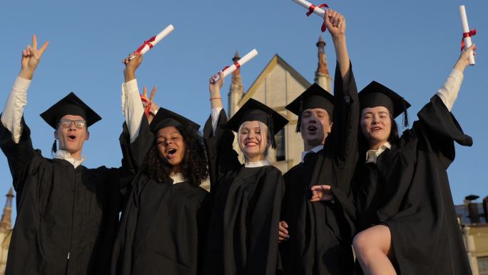 一群快乐的学生在毕业典礼上举起双臂