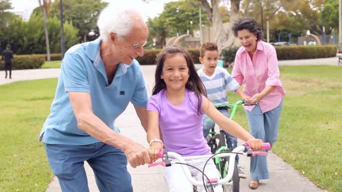 祖父母教孙子孙女在公园里骑自行车