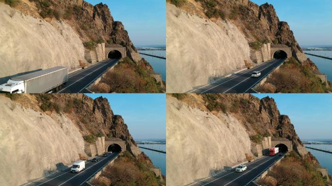 卡车、面包车和汽车进出穿越山体的隧道。
