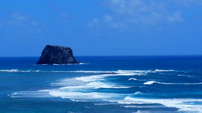 岩石岛前大浪滚滚热带鸟盘旋的航拍素材