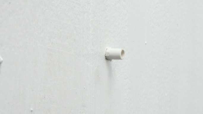 将塑料楔子插入白墙中，并用锤子敲击
