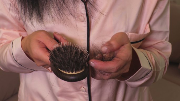 女人从手中的梳子上取下头发。