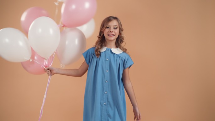 卷发的可爱女孩手持粉色和白色的气球