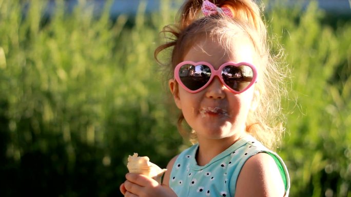 小女孩戴着太阳镜吃冰淇淋。
