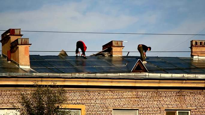 两个屋顶工人在屋顶上工作