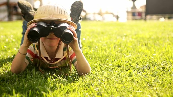 小男孩在草地里用望远镜