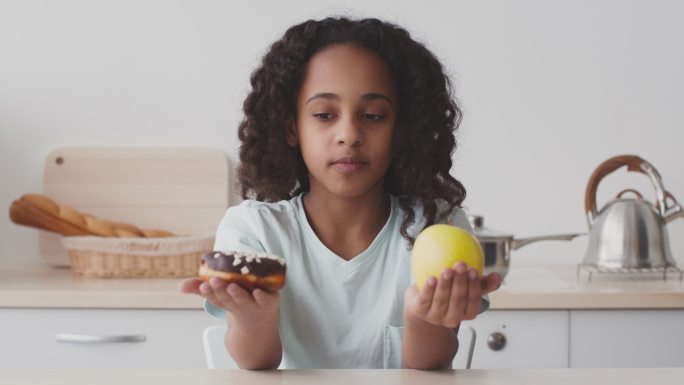 健康的饮食习惯。女孩对比甜甜圈和苹果