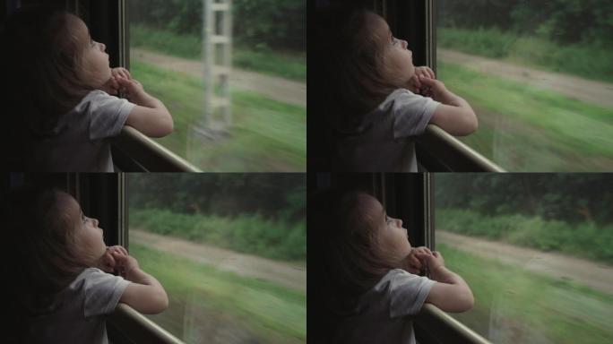 可爱的小女孩从火车窗口向外看的照片。