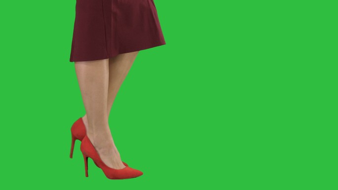 穿着红色高跟鞋的女人在绿色屏幕上行走