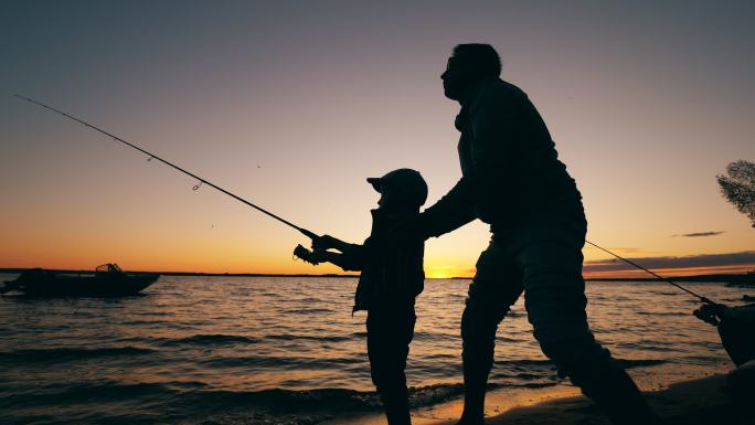 一个男人和他的儿子在日落时钓鱼