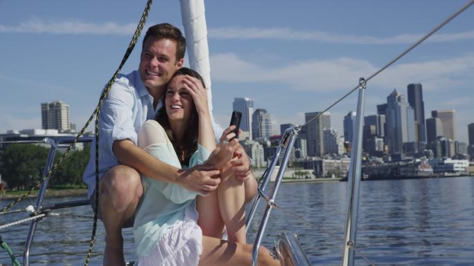 年轻夫妇在帆船上一起使用手机。