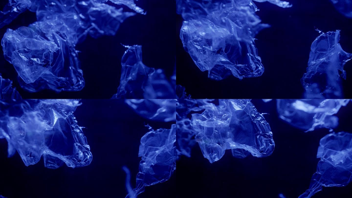 在黑暗的水中漂浮着发光的蓝色塑料的慢镜头