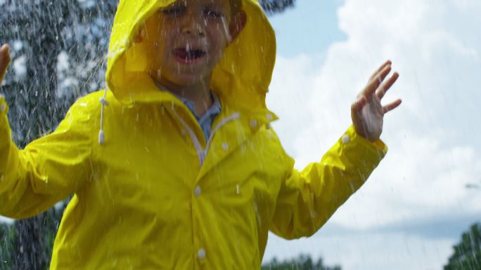 在水坑里跳的男孩小男孩经历风雨风吹雨打