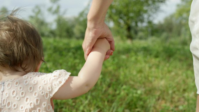 慢镜头：小女婴牵着妈妈的手在公园里散步