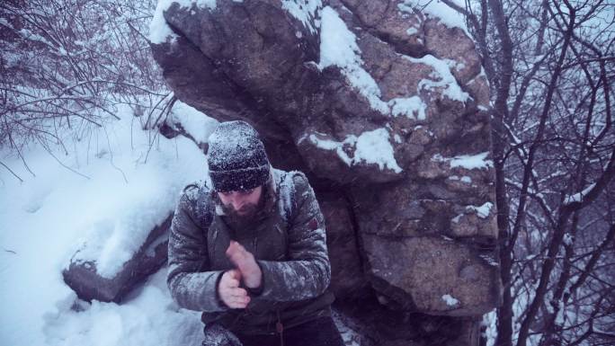 一个人试图在冬天的树林里攀爬岩石
