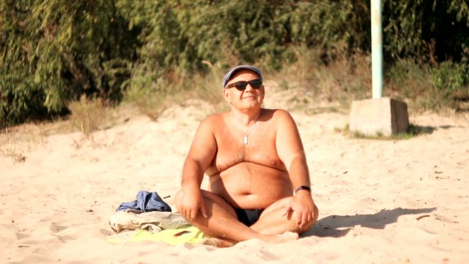 大腹便便的男人正在海滩上休息。