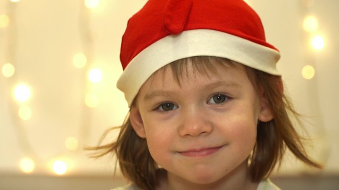 戴着红色圣诞老人帽子的小女孩看着相机