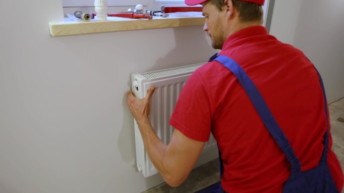 水管工在家里的墙上安装暖气片