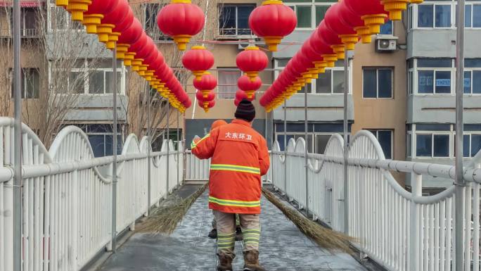 冬季北方环卫工人清扫挂着红灯笼的过街天桥