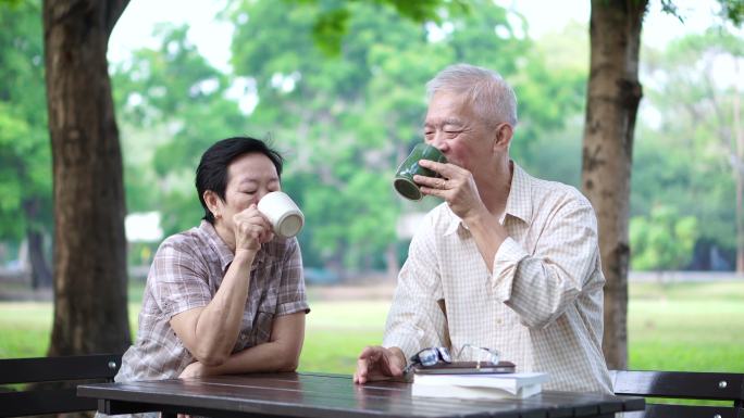 老年夫妇在公园喝咖啡看书