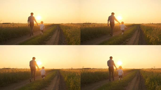 父亲和小男孩在日落时走在田野上。