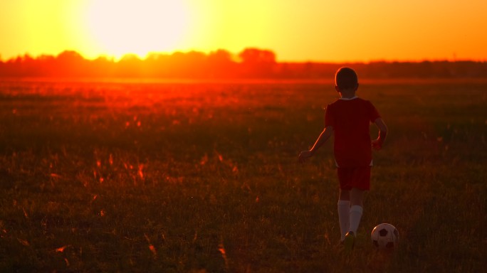 日落时分，一名男子足球运动员在球场上踢球