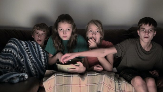 四个青少年坐在沙发上看恐怖电影