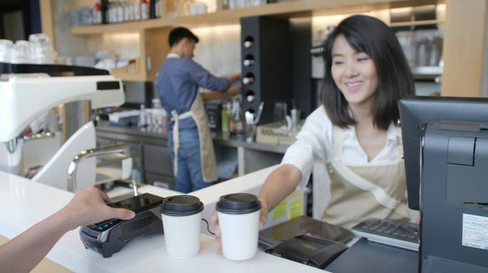 顾客在咖啡馆里使用手机支付费用购买咖啡