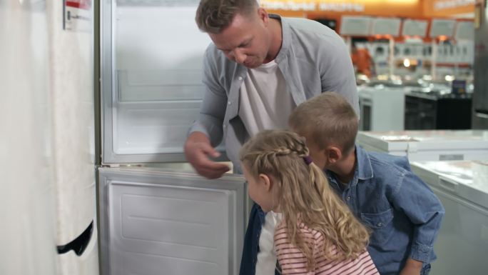 爸爸和孩子们在家电店看冰箱