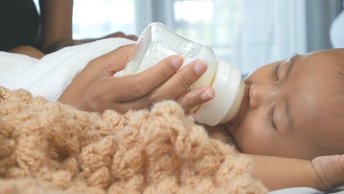 可爱的新生女婴睡觉和吮吸奶瓶