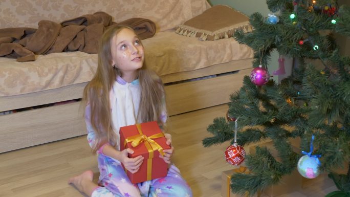 可爱的小女孩在家里打开圣诞礼物