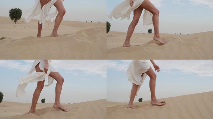 一个赤脚的女人穿着白色的衣服在沙漠散步