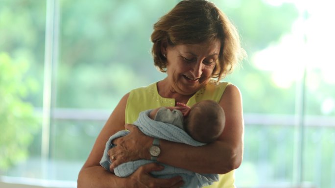 快乐的祖母平静地抱着新生婴儿