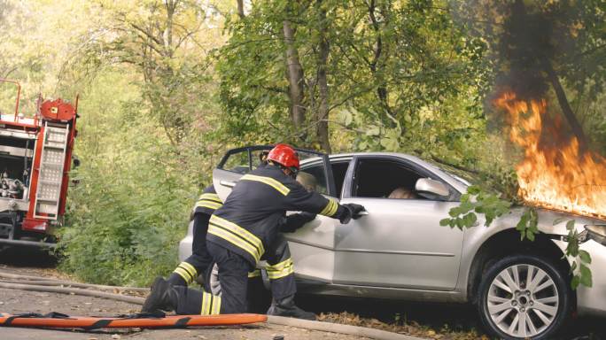 消防队员急忙从燃烧的汽车中救出乘客