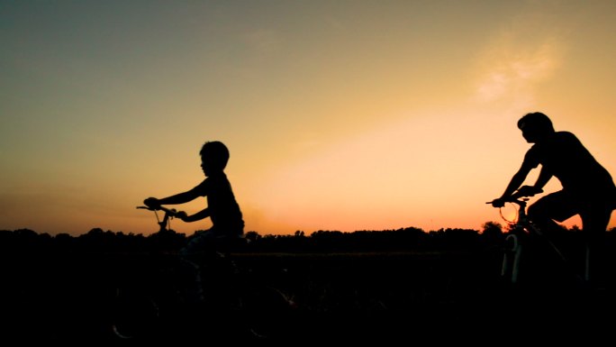 日落时分，父亲和孩子骑自行车