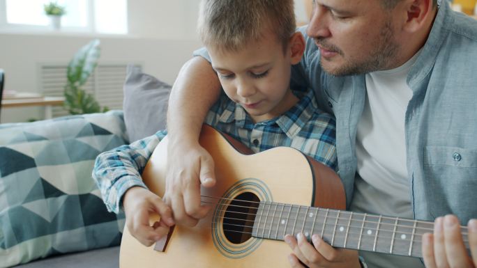 在公寓里教儿子弹吉他的年轻人