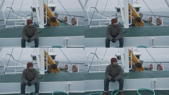孤独的渔夫坐在商船的长凳上。