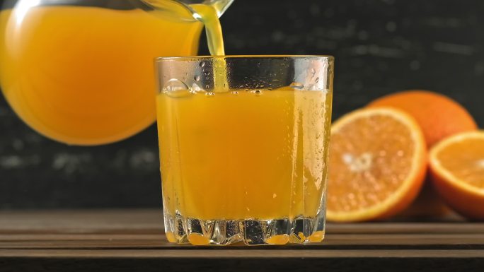 橙汁倒在玻璃杯里，加入冰块和水