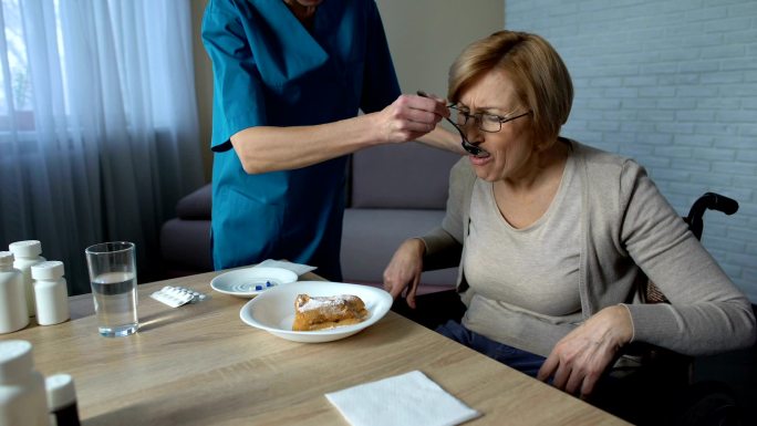 女护士帮助残疾老太太吃饭