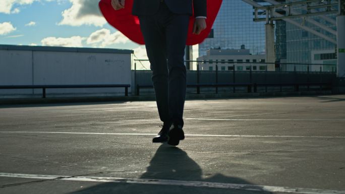 穿着红色披风的商人超级英雄走在屋顶上