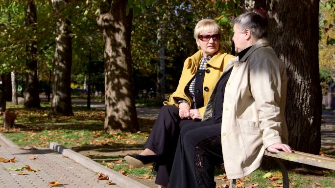 老年妇女在城市公园的长椅上聊天